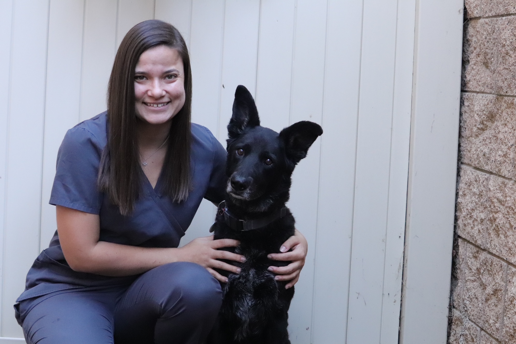 female in scrubs with large black dog